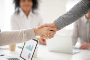 business partners handshaking at group meeting making project investment closeup